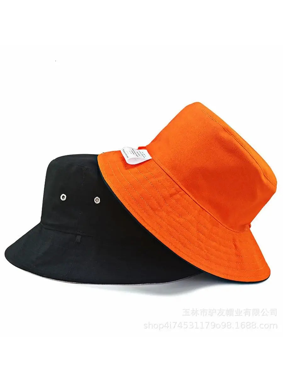 Oversize cotton bucket hats in orange and black with wide brims. Unisex design provides breathable comfort and bold summer style.