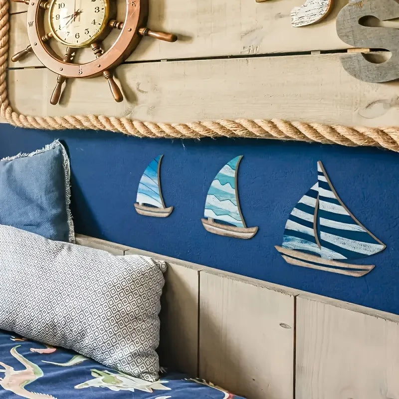 Wooden Sailboat Wall Art Set mounted on a navy blue wall above a nautical-themed bed. Perfect for ocean-inspired bedroom decor.