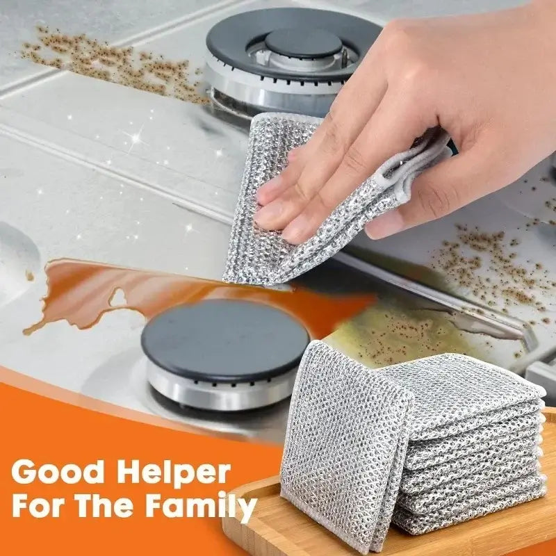 Magic Dishcloth Silver Wire wiping stove spills, labeled as a good helper for the family with stacked cloths in the background.