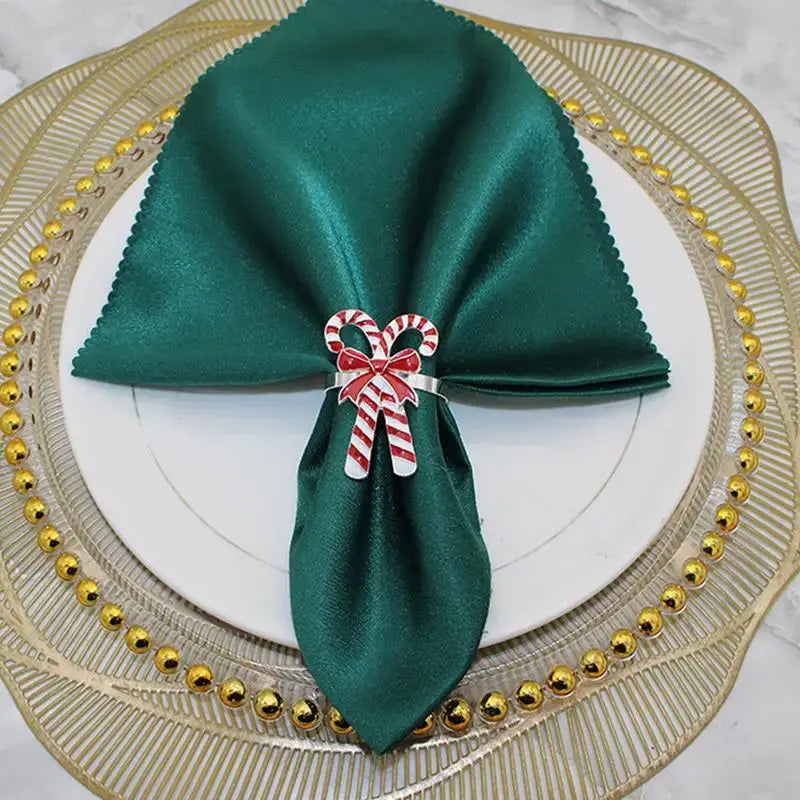 Candy Cane Napkin Rings - Christmas Napkin Holders displayed on a green napkin over a white plate with gold charger, perfect for festive dining.