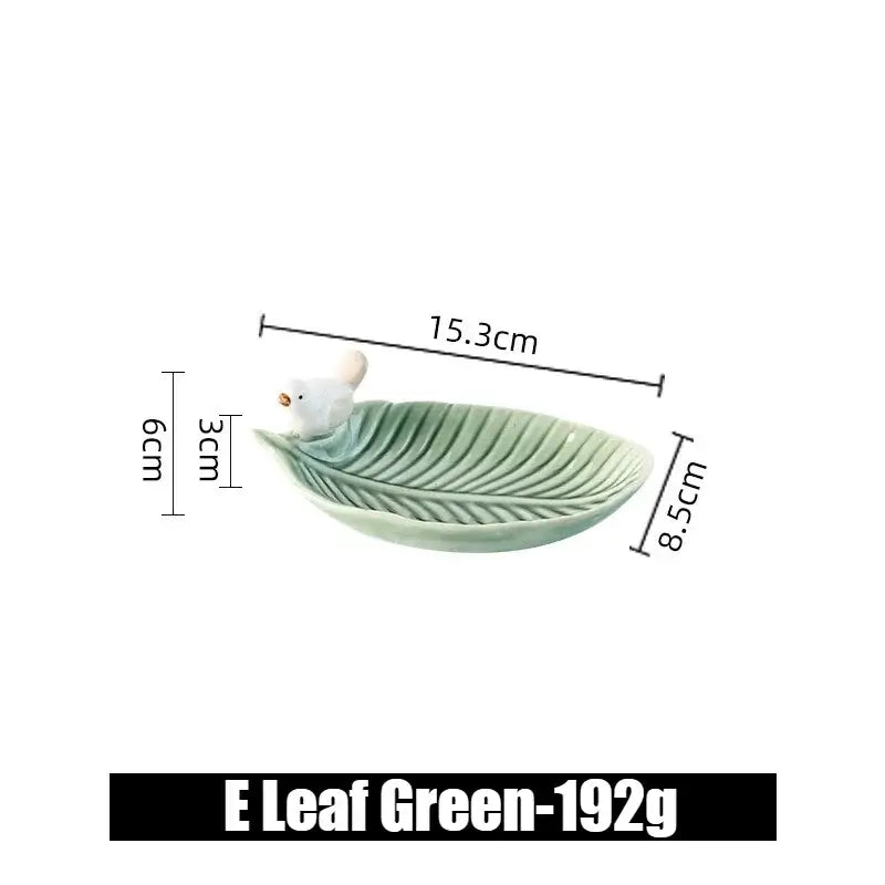 Green ceramic leaf jewelry tray with a single bird figurine, labeled E Leaf Green, perfect for small accessory storage.
