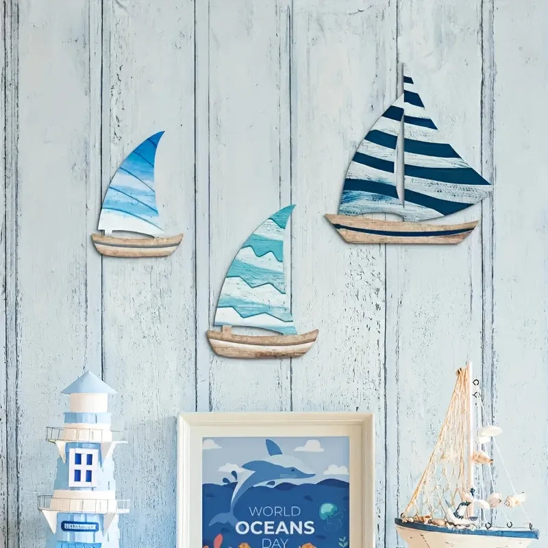 3PCS Wooden Sailboat Wall Art displayed on a light wood panel wall with ocean-themed decor. Enhances nautical room aesthetics.