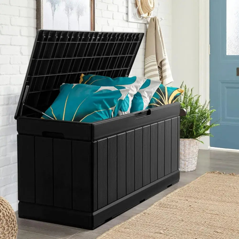 83 Gallon Outdoor Deck Box with open lid showing teal cushions inside. Multi-functional resin storage for patio or indoor use.