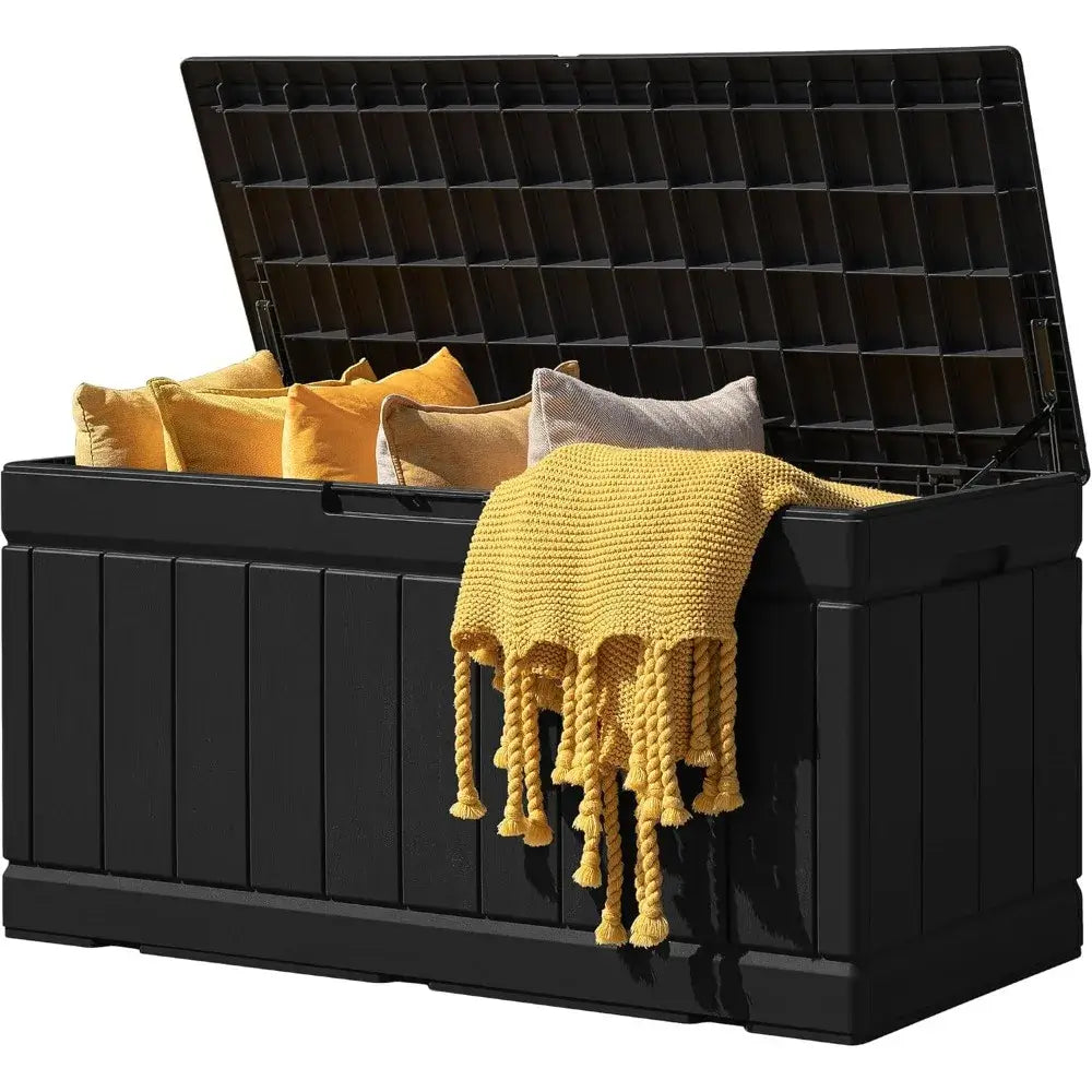 Large 83 Gallon Outdoor Storage Box in black resin with yellow pillows and throw blanket. Ideal for deck or garden organization.