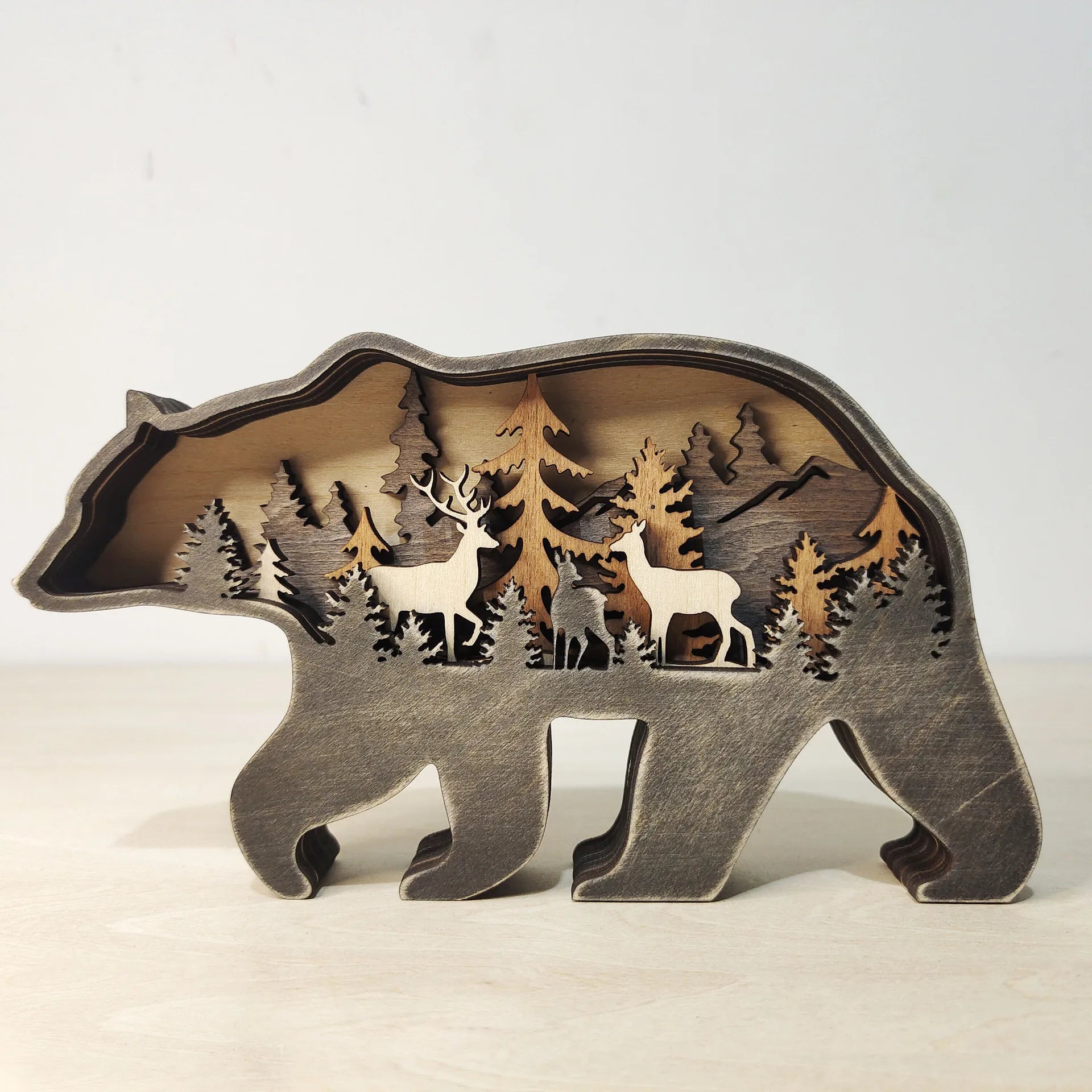 Rustic wooden bear figurine featuring layered forest and deer design, perfect carved wooden art for home or office display.