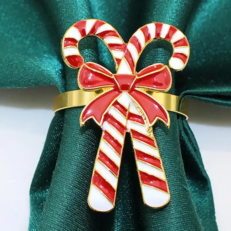 Candy Cane Napkin Rings - Christmas Napkin Holders featuring red and white enamel candy canes with a bow on a green napkin. Adds festive charm to holiday table decor.