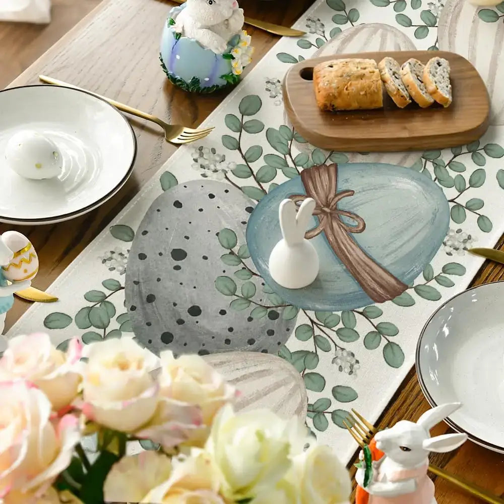 Close-up of Easter table runner with painted eggs and eucalyptus leaves under spring-themed tableware. Soft linen for seasonal elegance.