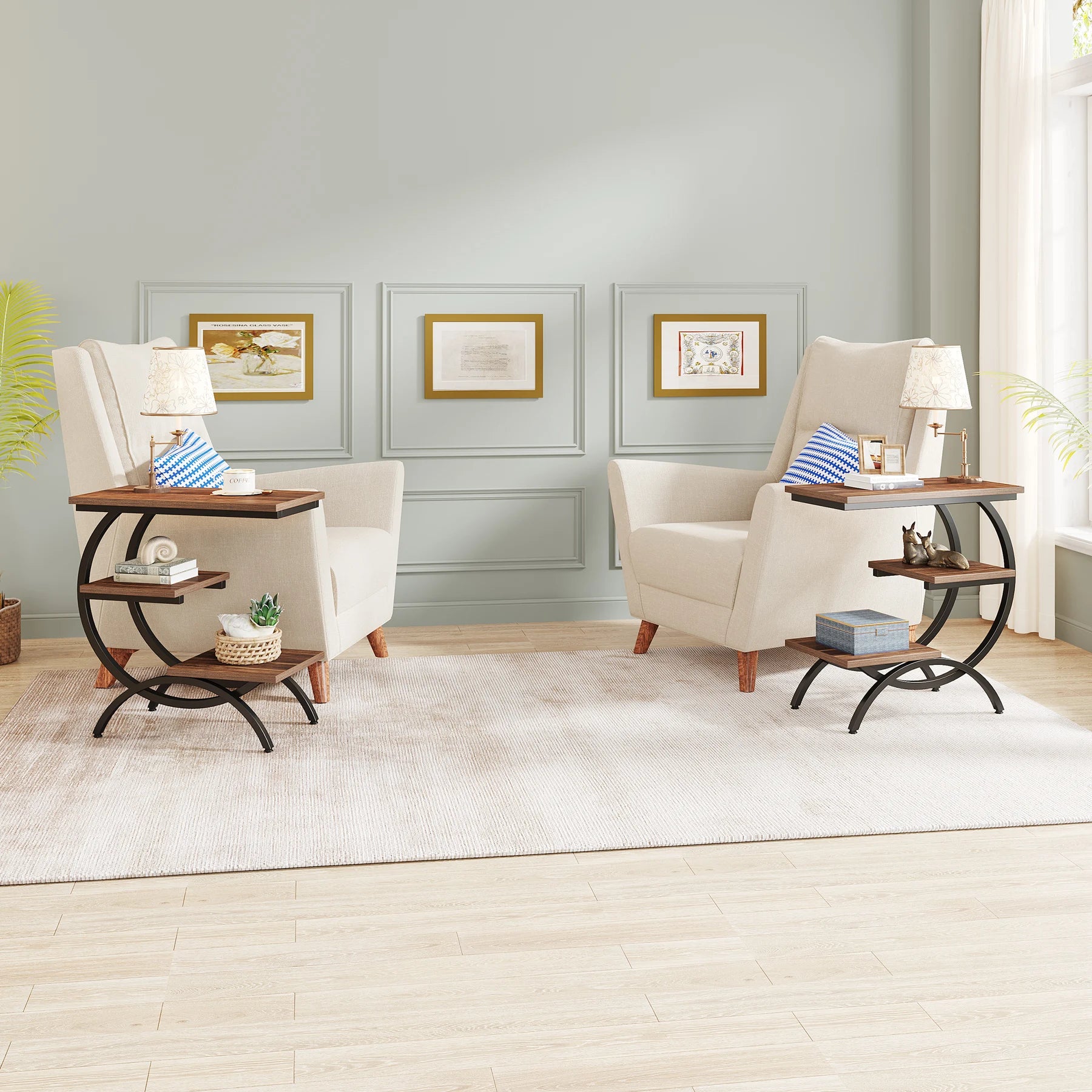 Pair of industrial 3-tier couch tables in a modern living room, placed between two beige armchairs with lamps and decor.