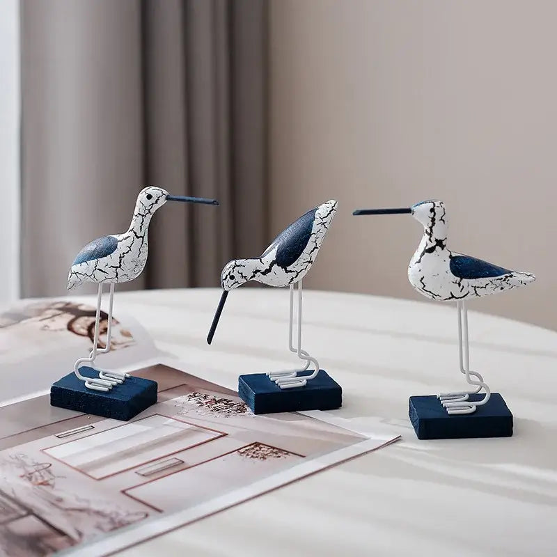 Set of 3 wooden seagull figurines with distressed paint, ideal for enhancing beach-themed home decor in living rooms or bedrooms.