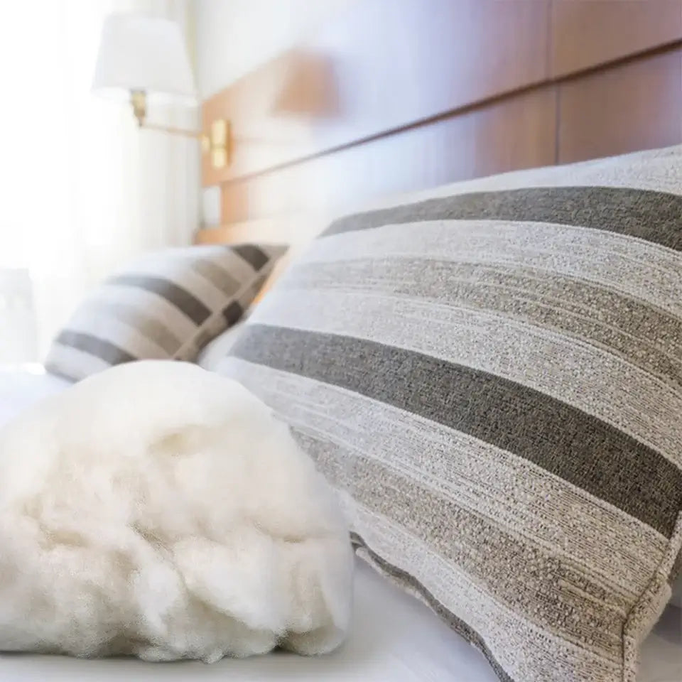 KRABALL Polyester Fiberfill placed near striped pillows on a bed. Soft and fluffy stuffing for cushions and bedding.