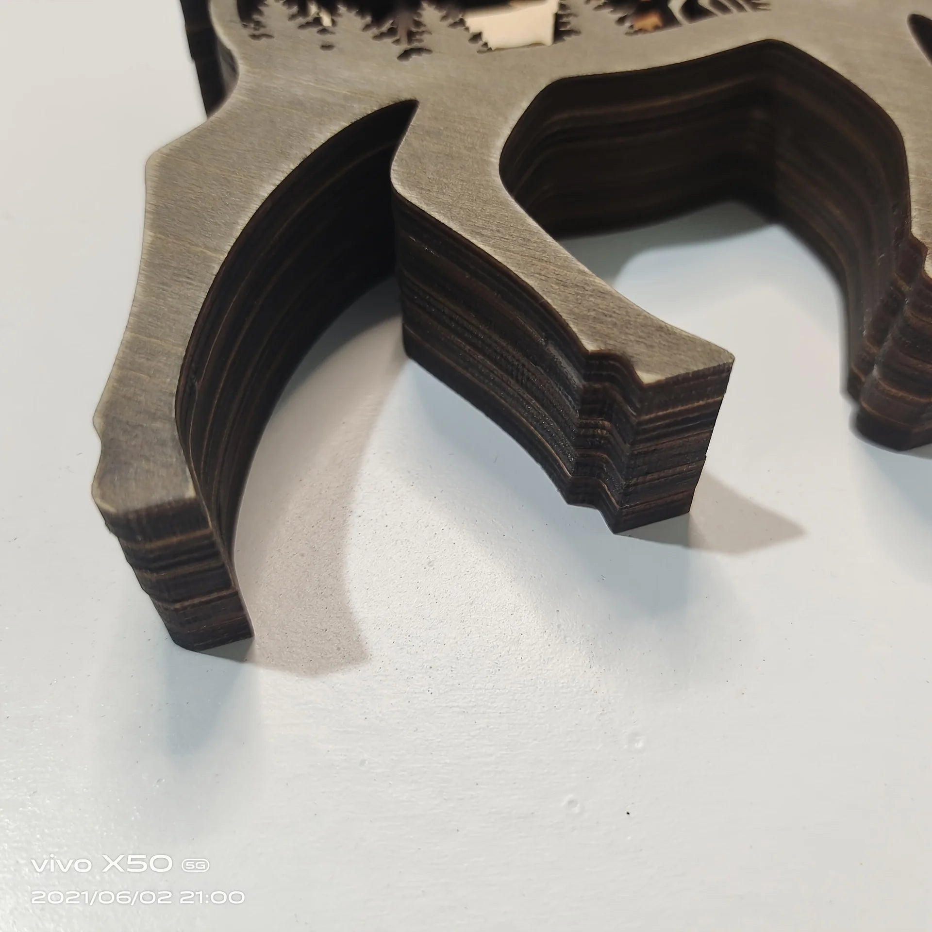 Detailed view of bear figurine's layered wooden legs, showcasing craftsmanship and texture of rustic carved décor.