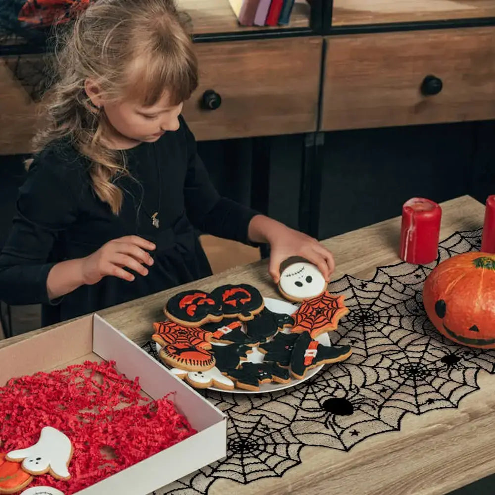 Child decorating Halloween cookies on a table with Spider Web Lace Table Runner, adding festive gothic charm to the holiday setup.