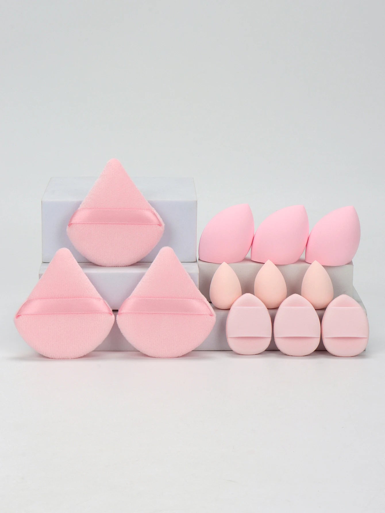 Light pink 12-piece makeup sponge set with triangle puffs and teardrop sponges. Designed for smooth, even makeup coverage.