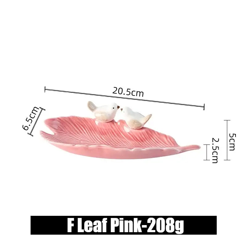 Side view of pink ceramic leaf jewelry tray with bird figurines, labeled F Leaf Pink, showing its elegant curved design.