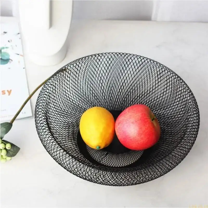 Black metal fruit basket holding lemon and apple, showcasing its large capacity and durable mesh design for kitchen use.