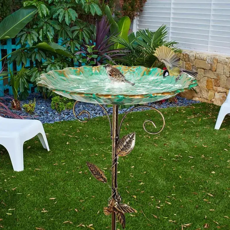 Leaf-patterned Metal Bird Bath Feeder in a landscaped garden, with birds enjoying the water in the green glass bowl.